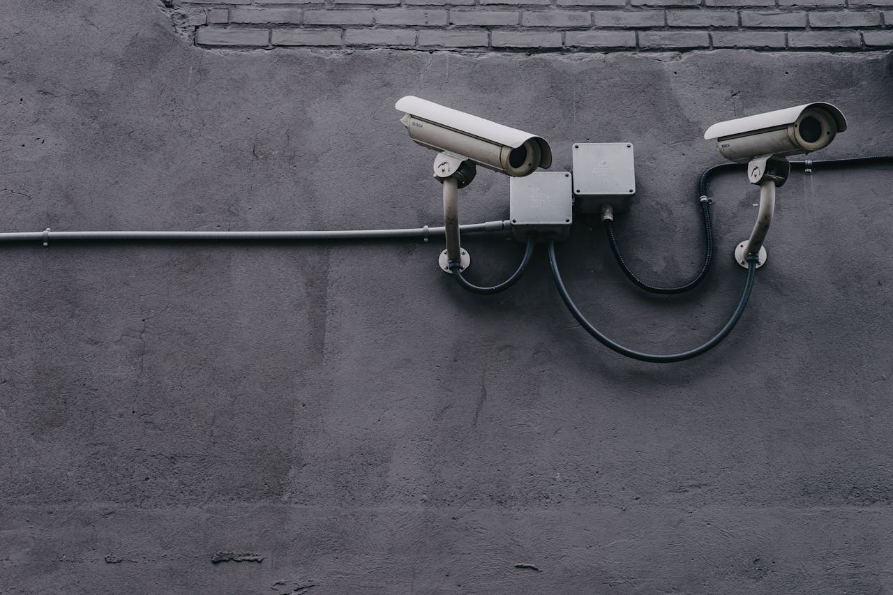 hero-about Two surveillance cameras mounted on a concrete wall, highlighting security technology.